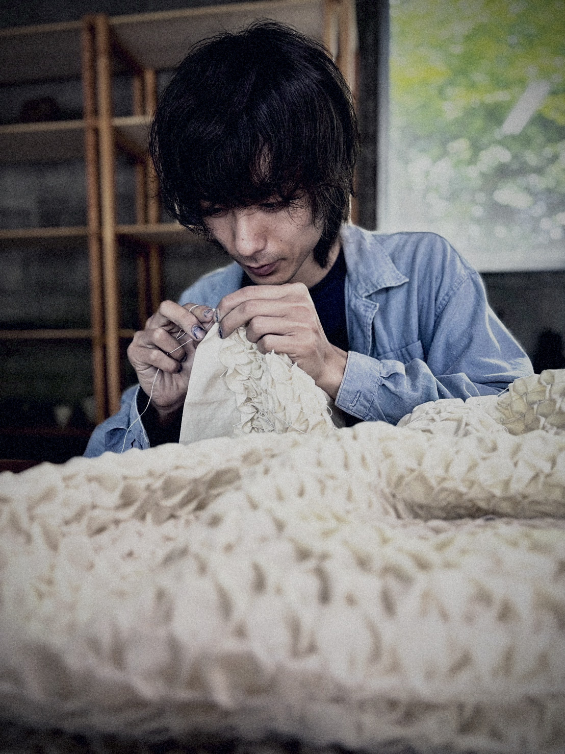 Artisan hand-stitching shibori resist patterns into white cloth