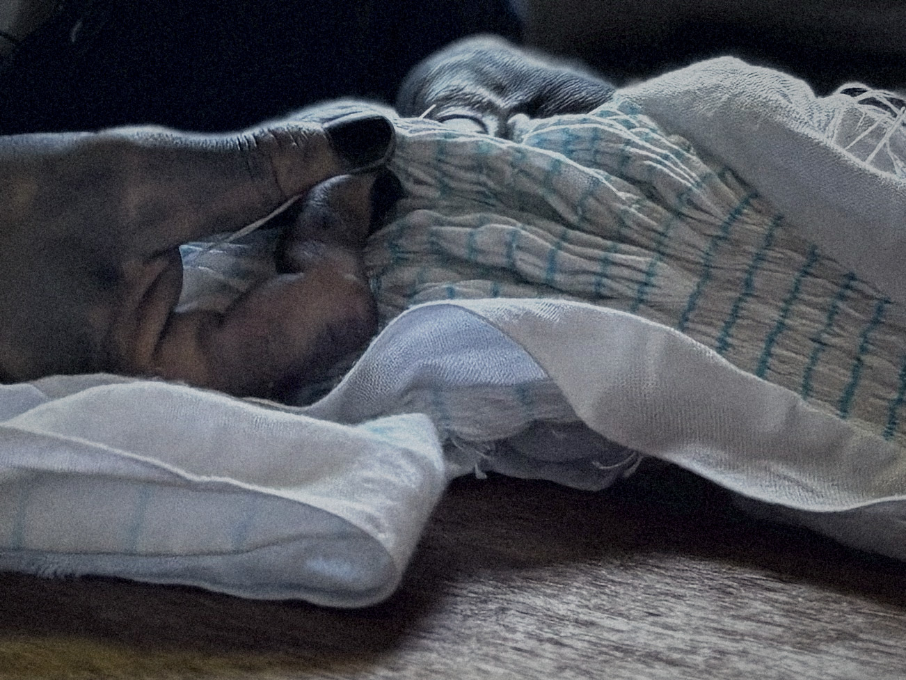 Indigo-stained hands loosening shibori stitching on dyed cloth